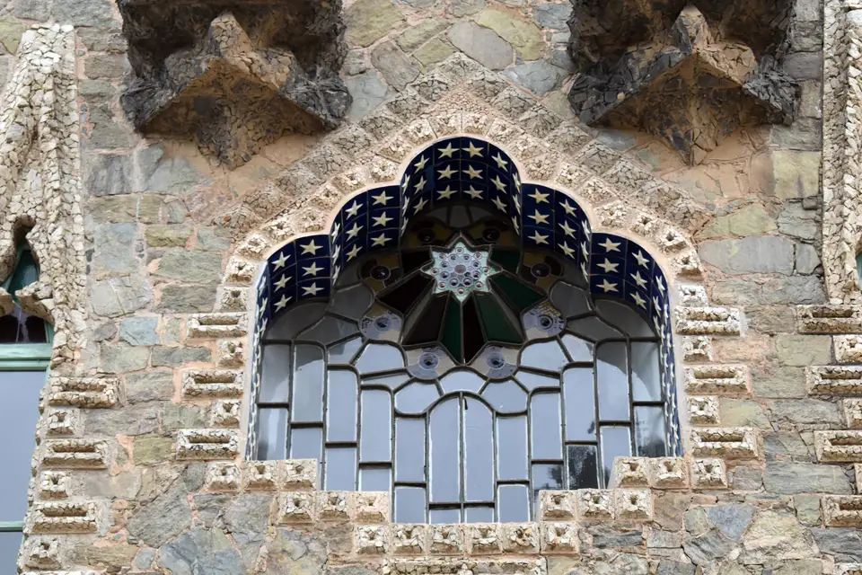 A Gaudí stained-glass window in the stone facade of Torre Bellesguard