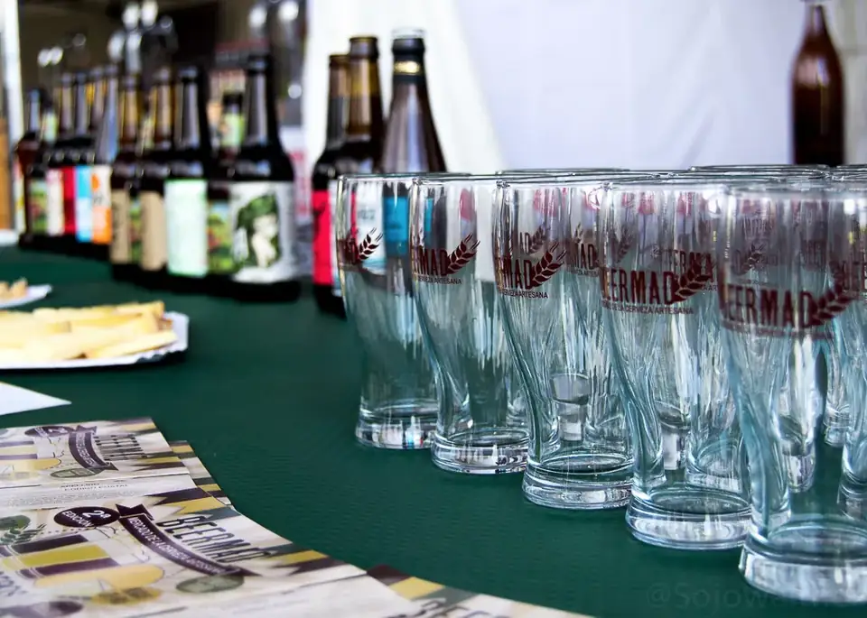 Rows of empty tasting glasses and craft beer bottles lined up on a table