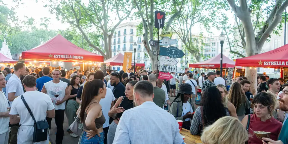 Crowds and red food stalls at the Born Street Food festival on Pla de Palau in El Born, Barcelona.