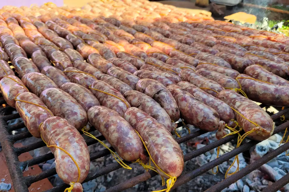 Rows of chorizos cooking on an asado grill
