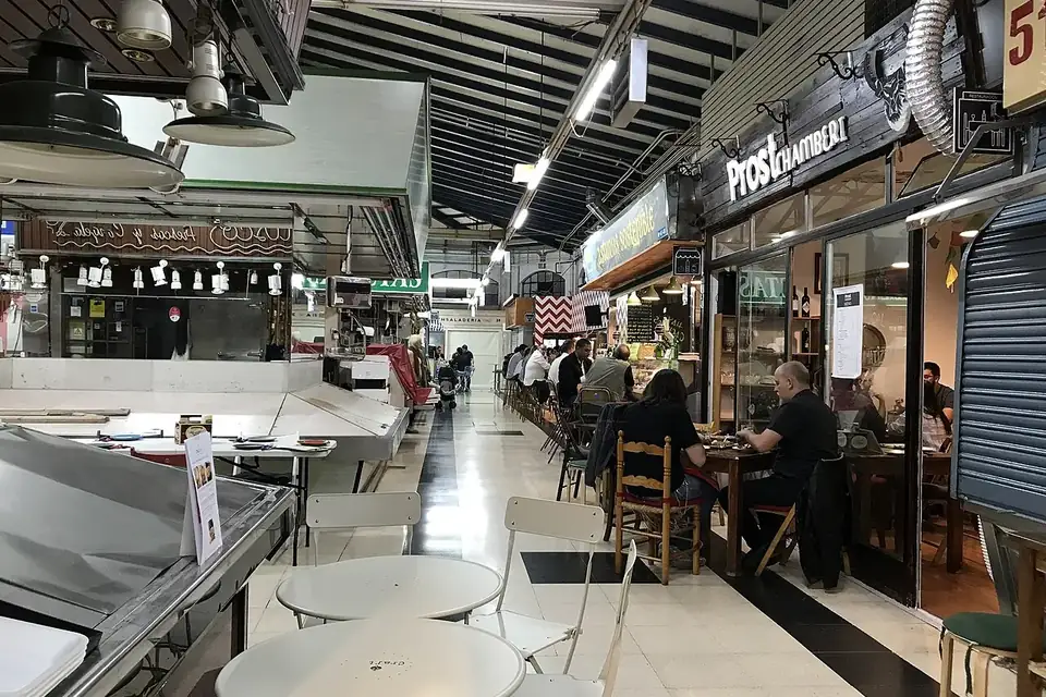 Market stalls and a seating area with café tables inside the Mercado de Vallehermoso