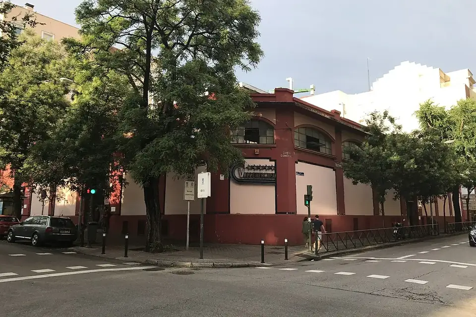 The red-brick exterior of the Mercado de Vallehermoso on a street corner lined with trees