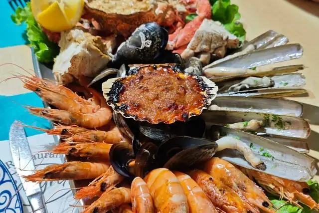 A seafood platter of prawns, razor clams, mussels, crab and a gratinated scallop on a restaurant table