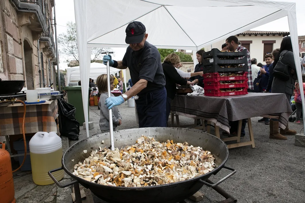 Chef cooking wild mushrooms in a giant pan at Festa del Bolet in Seva