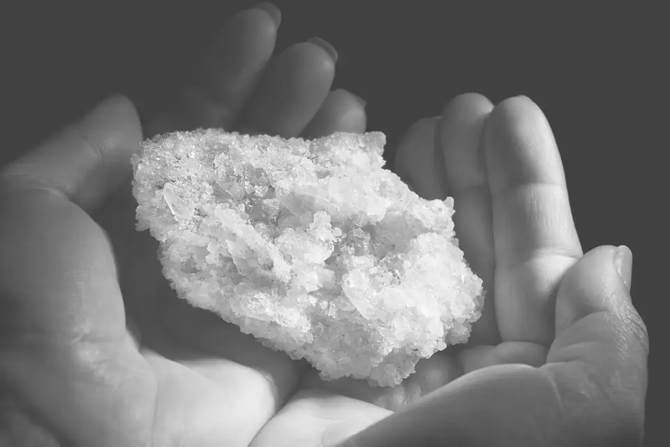 Two cupped hands holding a chunk of raw rock salt