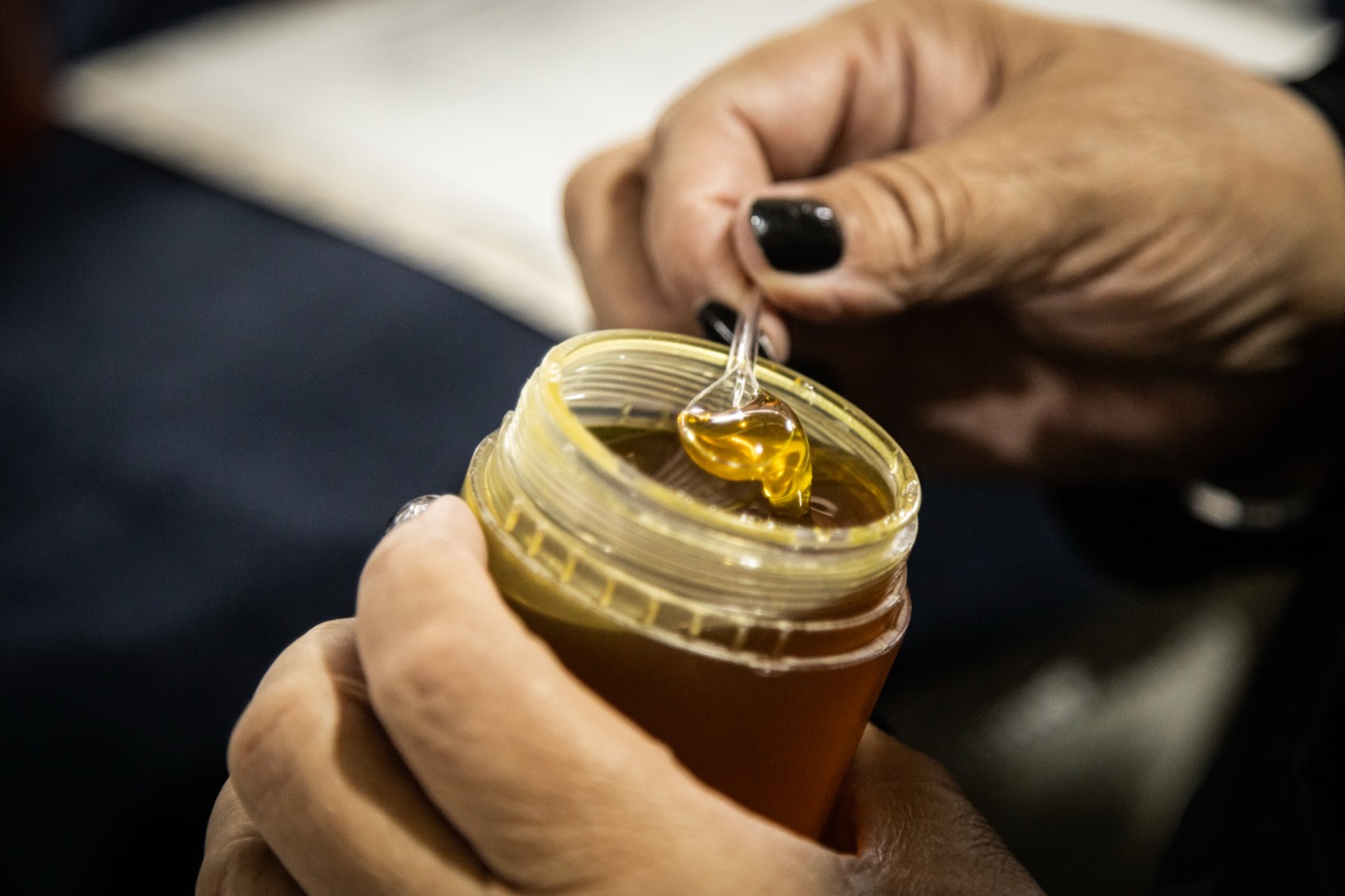 Golden honey lifted on a dipper from an open jar