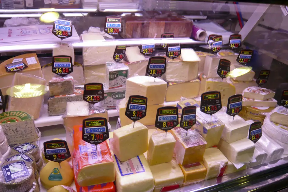 A market counter stacked with wedges and wheels of cheese