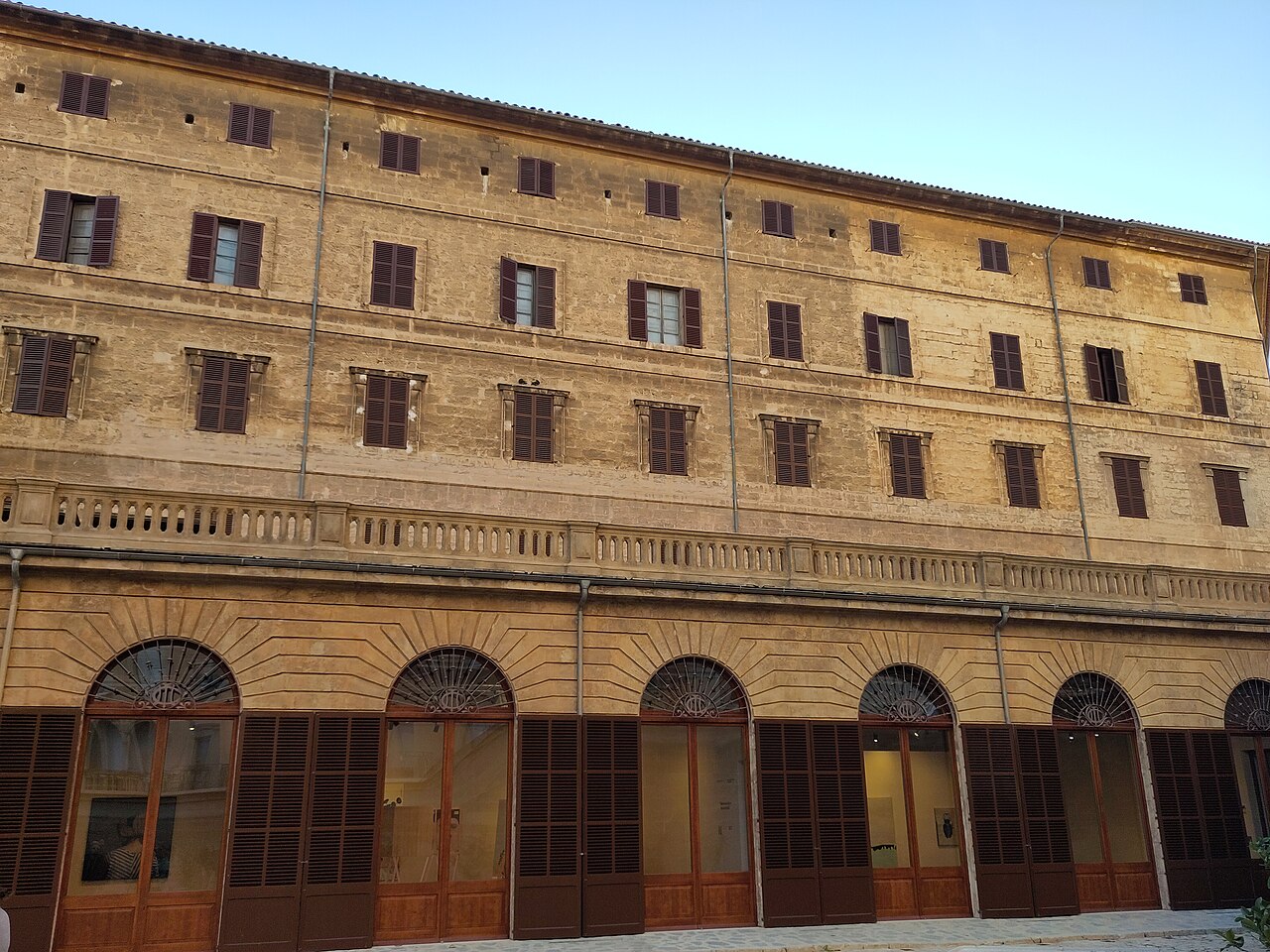 Sandstone facade of La Misericòrdia in Palma, with rows of shuttered windows above a ground floor of arched glazed doors