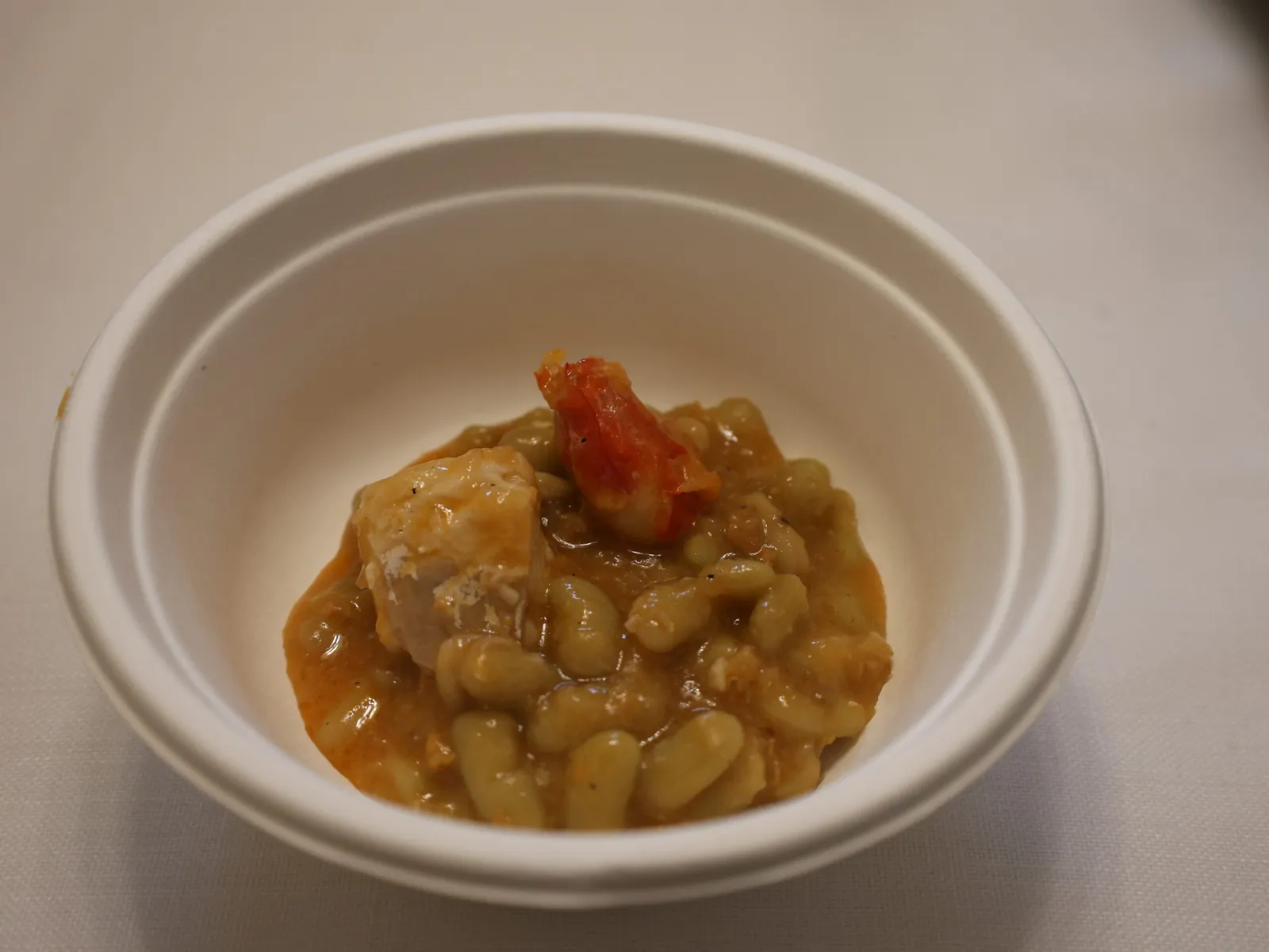 A white bowl of verdinas, small green Asturian beans, stewed with seafood