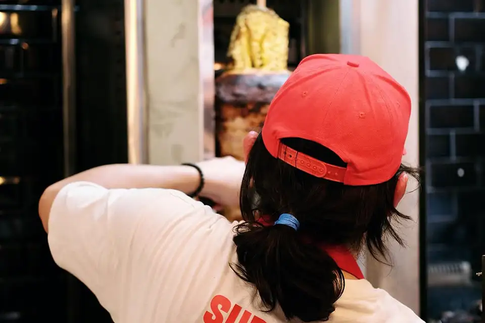 A cook in a red cap working the al pastor spit at Taco Fest Barcelona