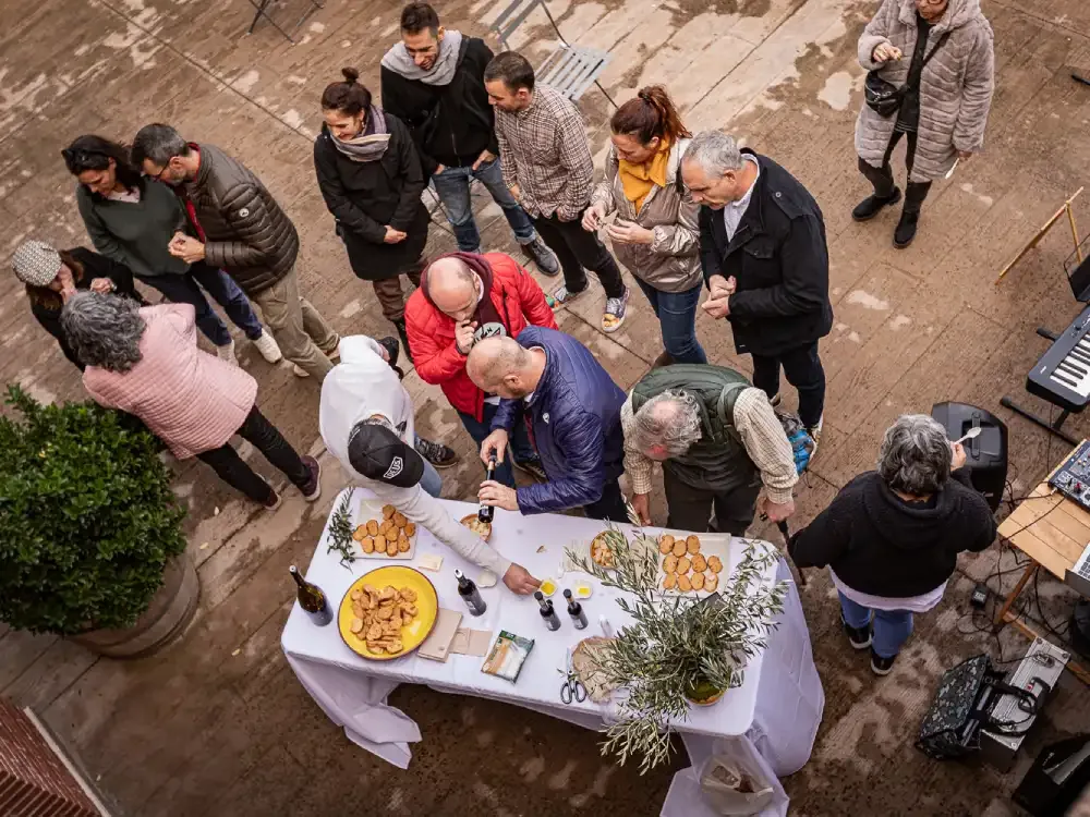 Visitors tasting wine and tapas at an outdoor table in the village square at Temps de Priorat Enoturisme in Escaladei