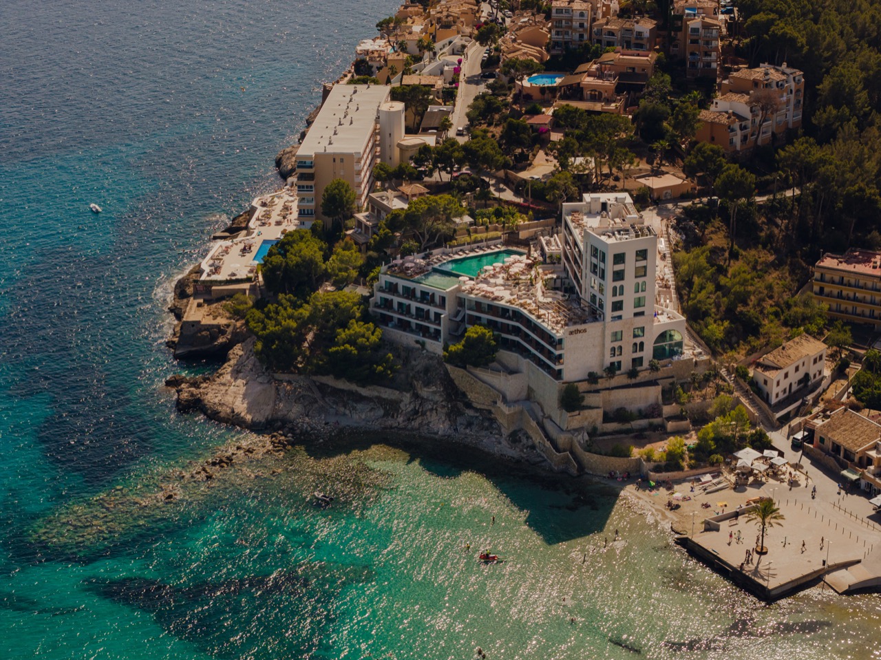 Aerial view of Aethos Mallorca perched on the cliff edge with its rooftop pool and the sea below