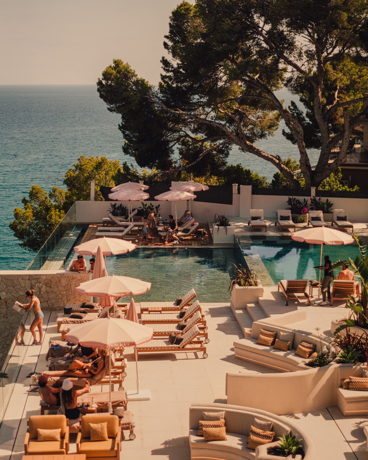Pool terrace at Aethos Mallorca with pink umbrellas, sun loungers and a sea view