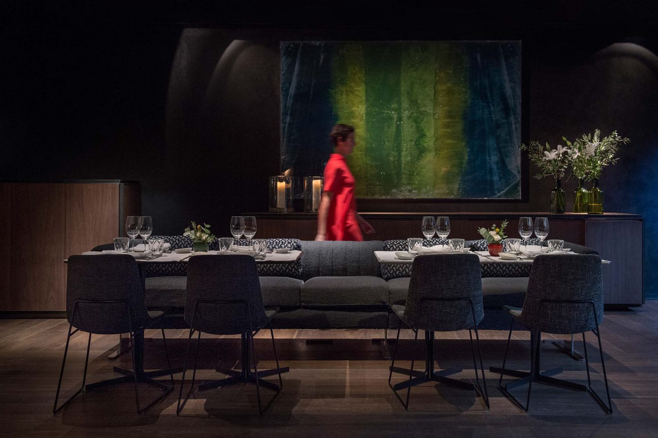 Restaurant interior with dark walls, dressed tables and a large abstract painting