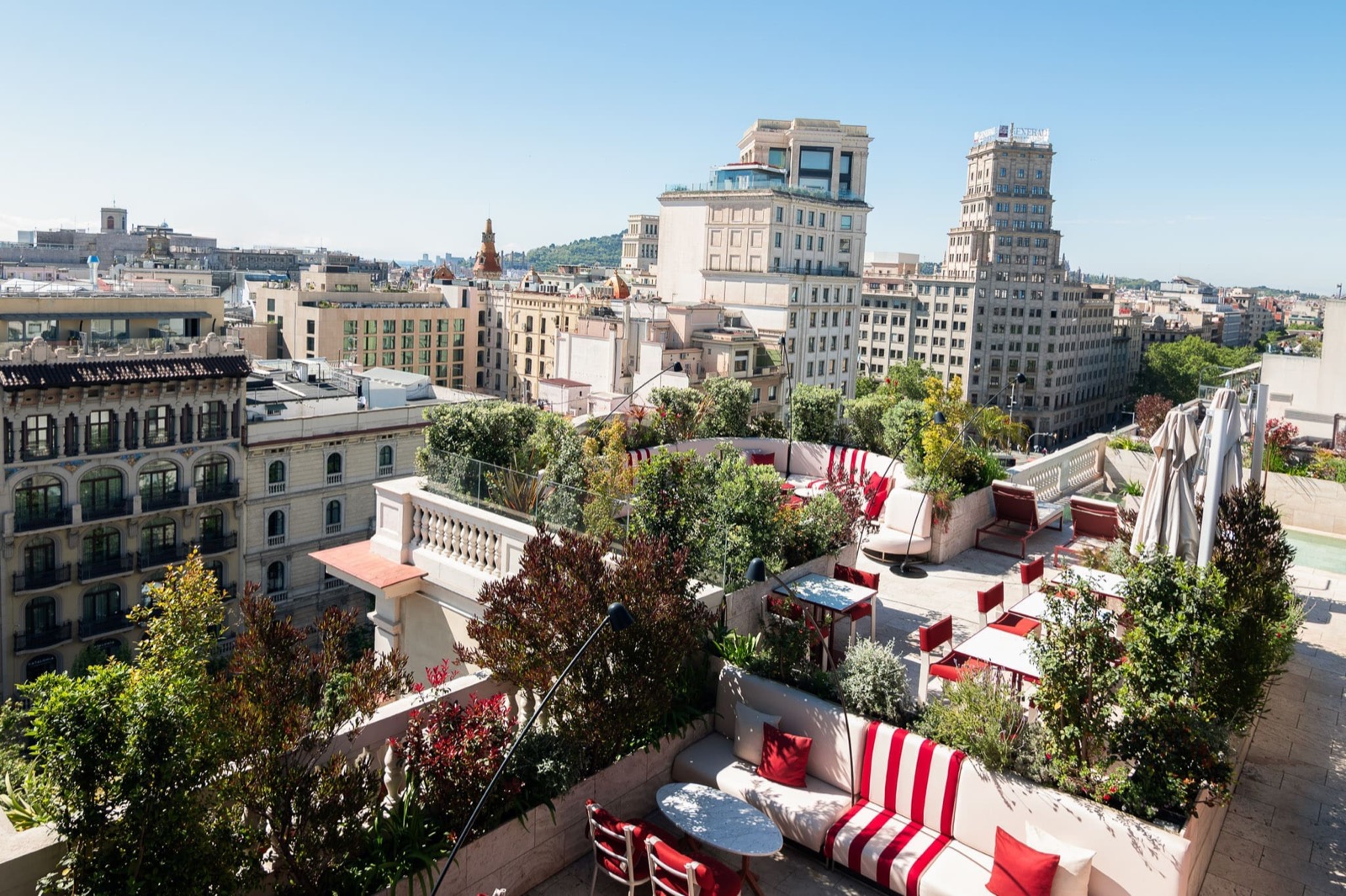 Azimuth rooftop terrace with red-and-white seating over Barcelona rooftops