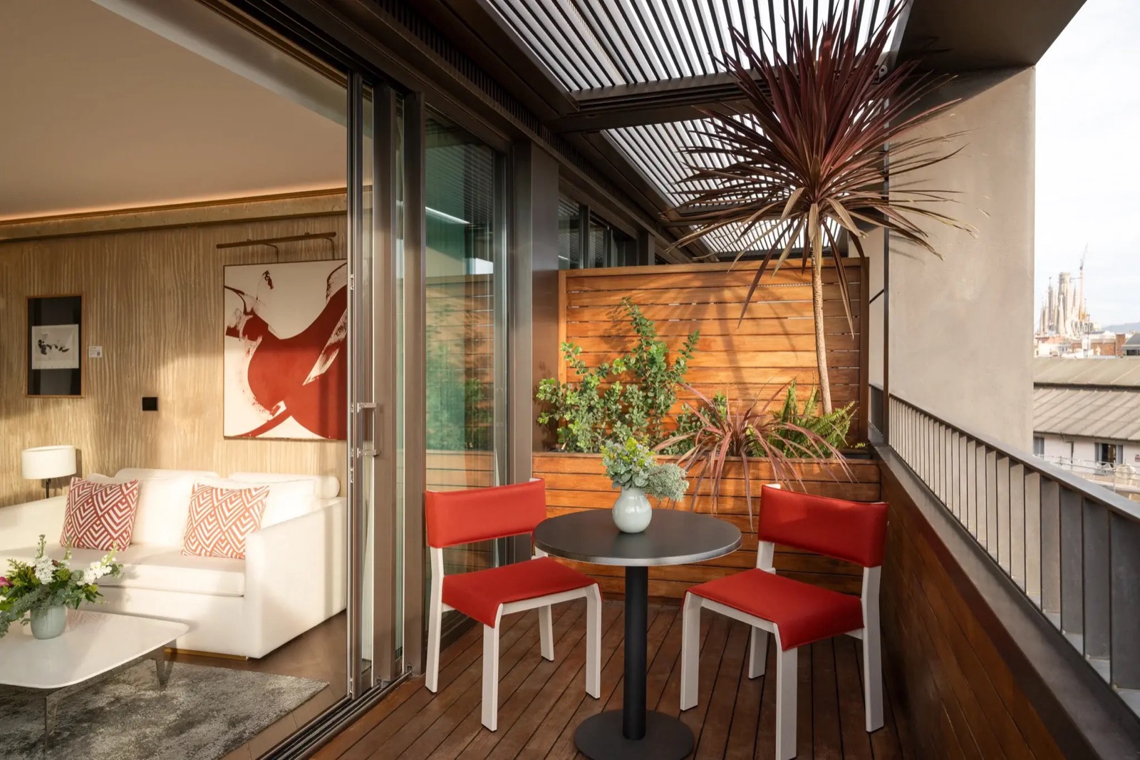 Private room terrace with red chairs and a distant view of the Sagrada Família