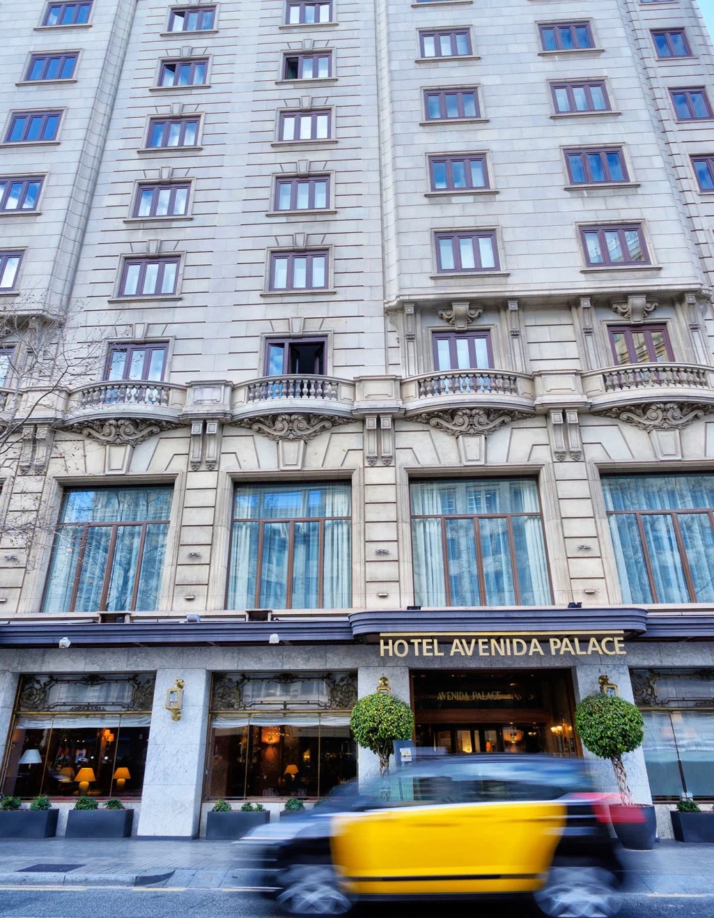 The stone facade of Hotel Avenida Palace on Gran Via de les Corts Catalanes, with its name in gold lettering above the entrance.