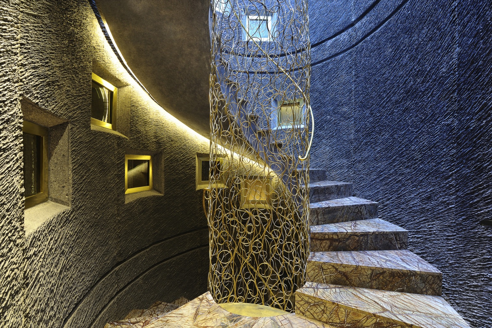 Sculptural spiral marble and brass staircase inside Hotel Bagués