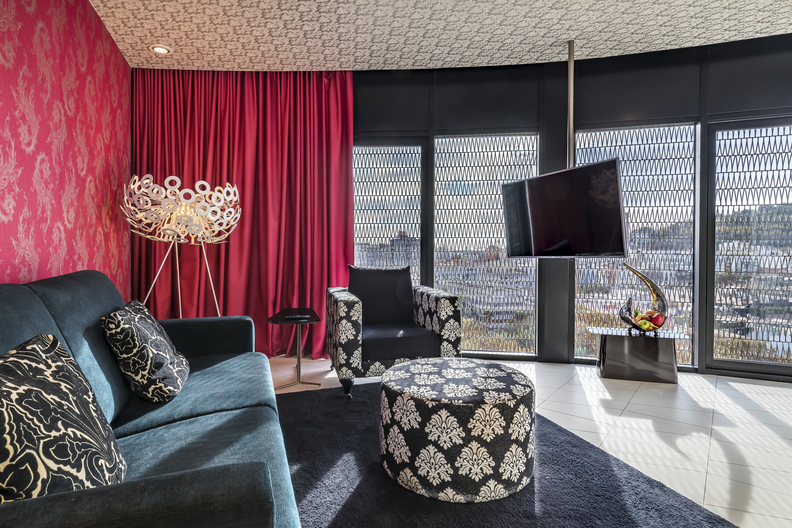 Junior suite living area with a teal sofa and city-view windows