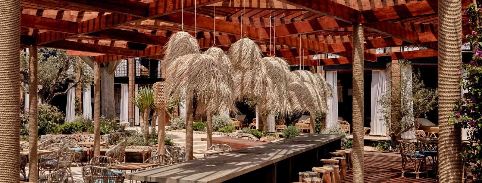 Pikkini Pool Bar at Bikini Island & Mountain with a long wood bar counter and stools under dramatic straw pendant light fixtures and a wood pergola roof