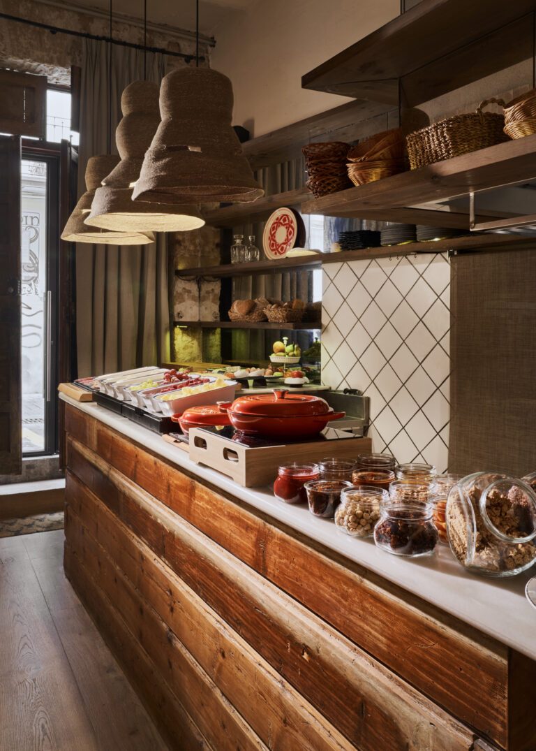 Breakfast counter at Posada Terra Santa with woven pendant lamps, jars of preserves and wicker baskets against a patterned tile backsplash