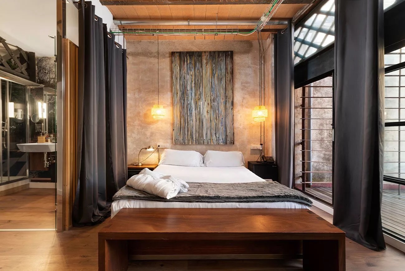 Loft-style guest room with an industrial ceiling, glass-walled bathroom and a private terrace