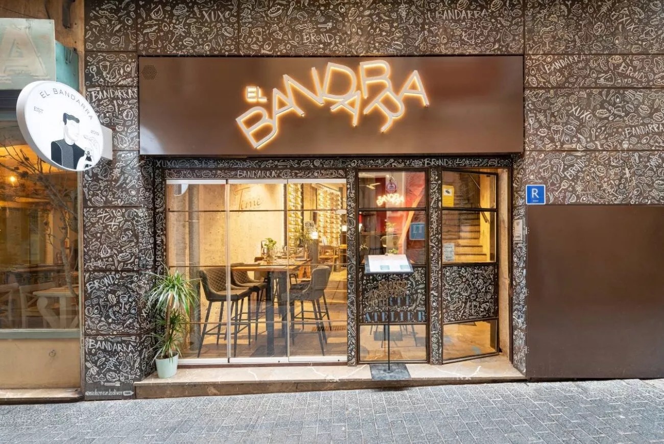 Street-level facade of El Bandarra, the hotel's on-site restaurant, lit sign above glass entrance