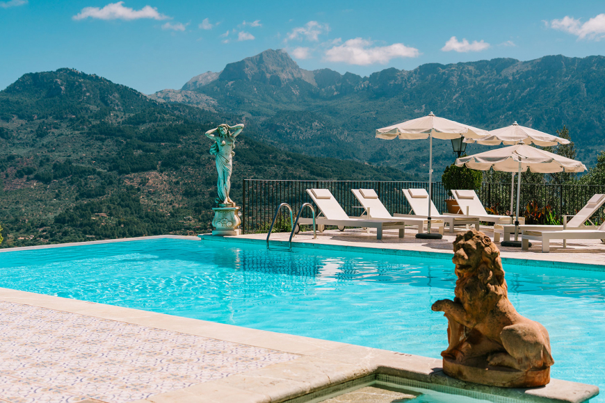 Outdoor pool with sun loungers, umbrellas and a view over the Tramuntana mountains