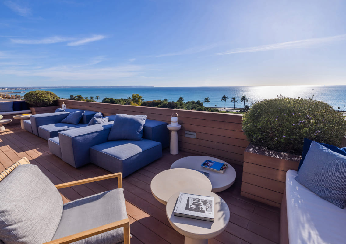 Rooftop terrace with blue sofas and loungers overlooking the sea and the coast