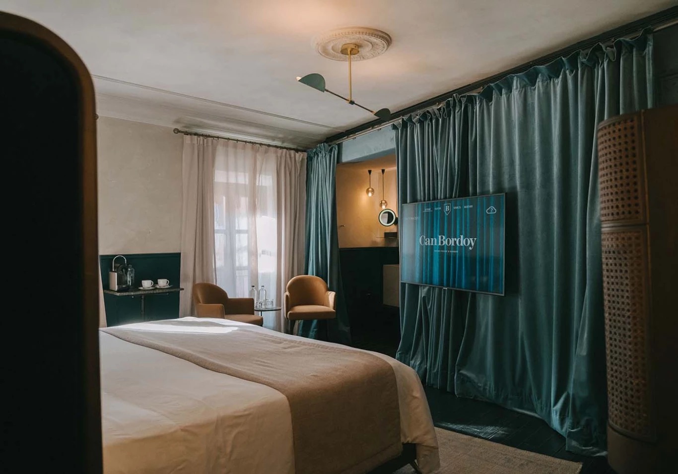 Junior suite bedroom with teal velvet curtains and armchairs