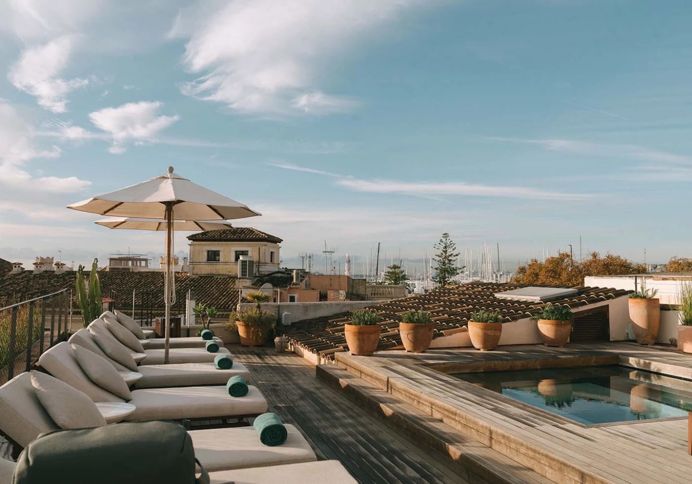 Rooftop pool with sun loungers overlooking Palma's rooftops and marina