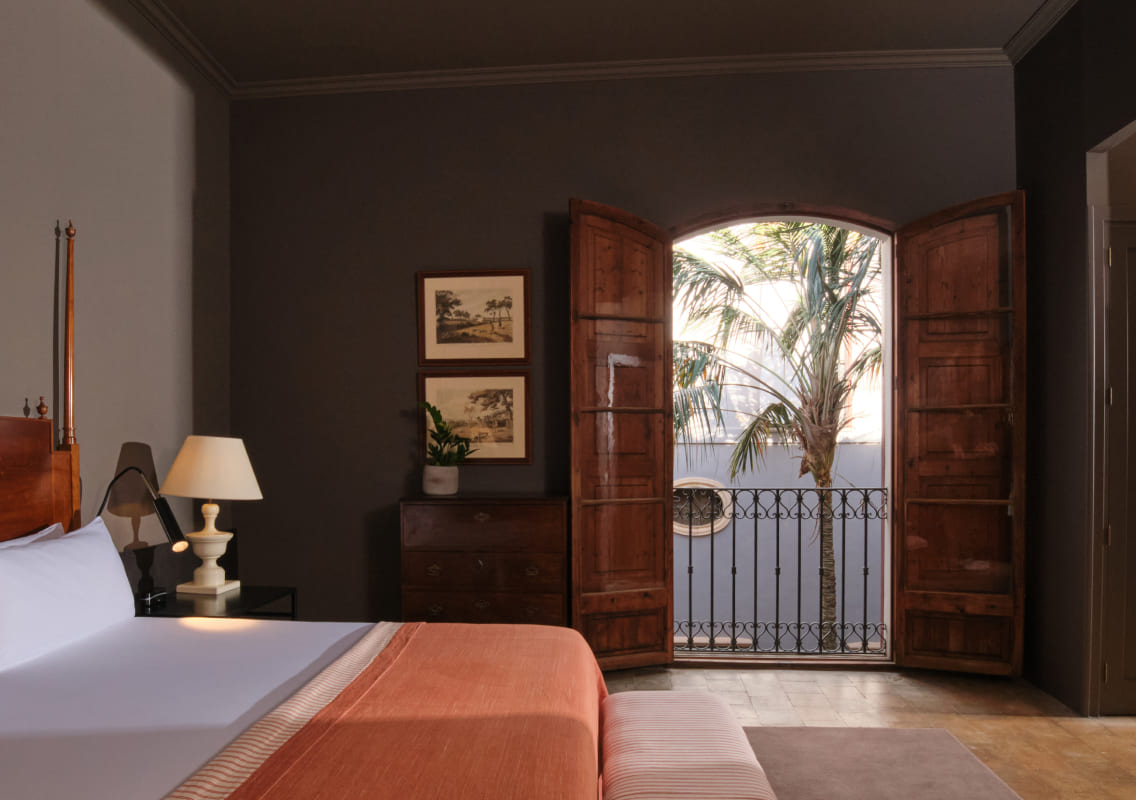Bedroom with open wooden balcony doors onto a small terrace