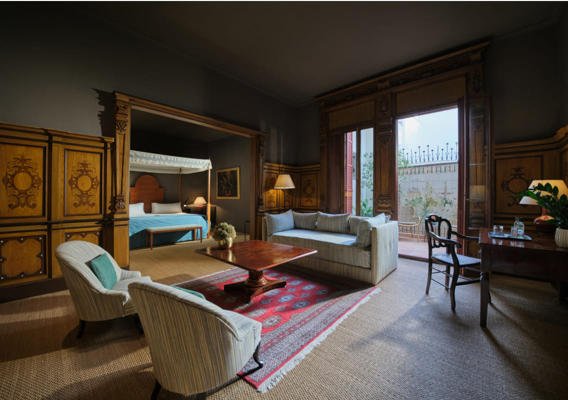 Suite with four poster bed and separate wood paneled sitting area