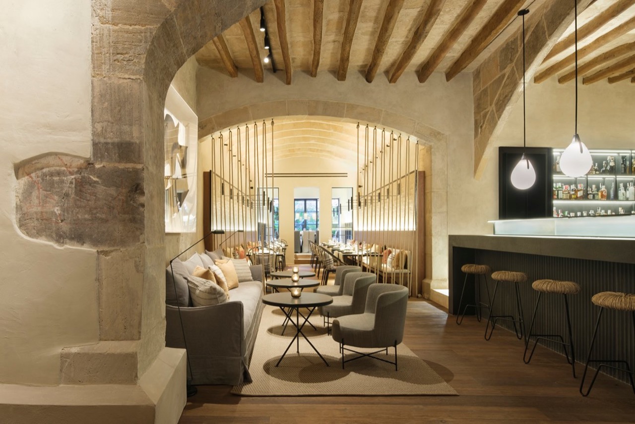Lounge and bar area at Can Ferrereta with stone archways, sofas, and bar stools under wood beams