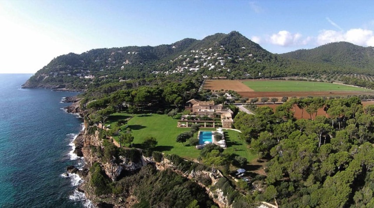 Aerial view of Can Simoneta on the cliffs above the sea, showing the main house, lawn and pool