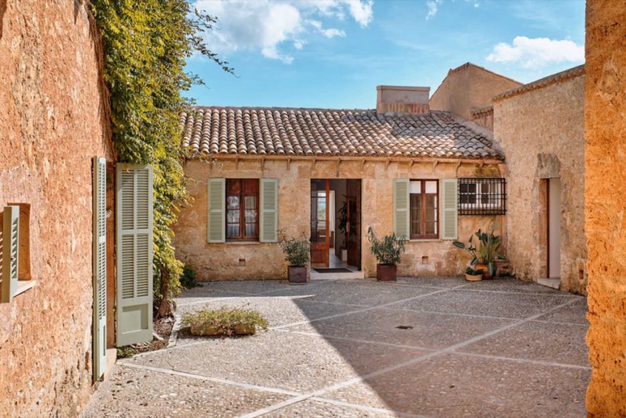 Stone courtyard exterior of the Can Simoneta finca with green shutters and climbing vines