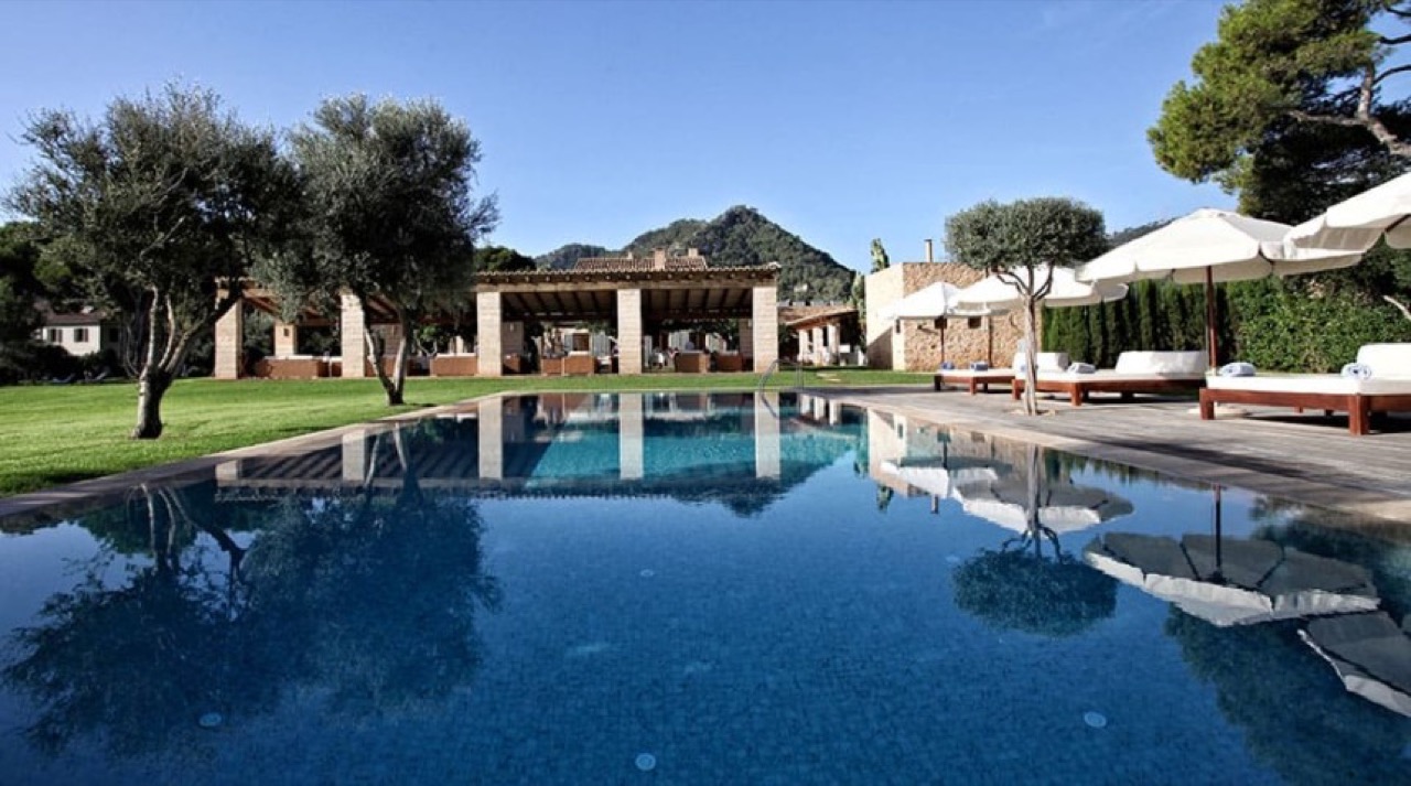 Swimming pool at Can Simoneta with a covered lounge pergola and mountains behind