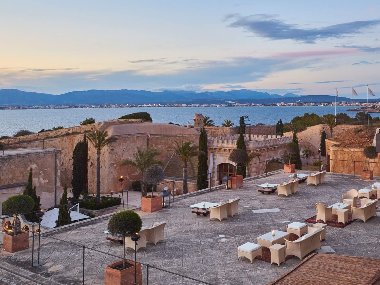 La Fortaleza restaurant terrace at Cap Rocat at sunset with fortress walls and the Bay of Palma beyond