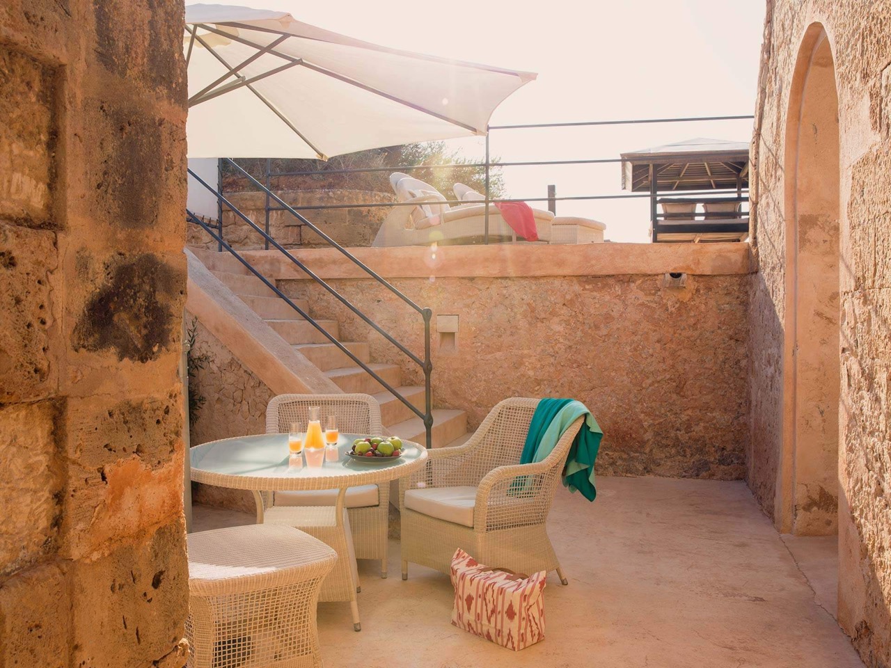 Private stone terrace at Cap Rocat with a dining table and sun loungers above