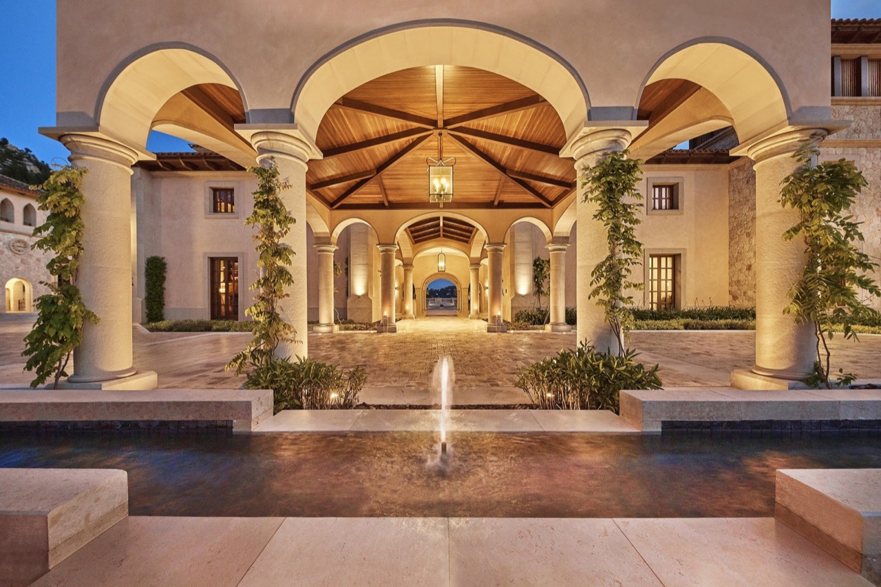 Cap Vermell Grand Hotel's covered stone entrance archway with a fountain at dusk