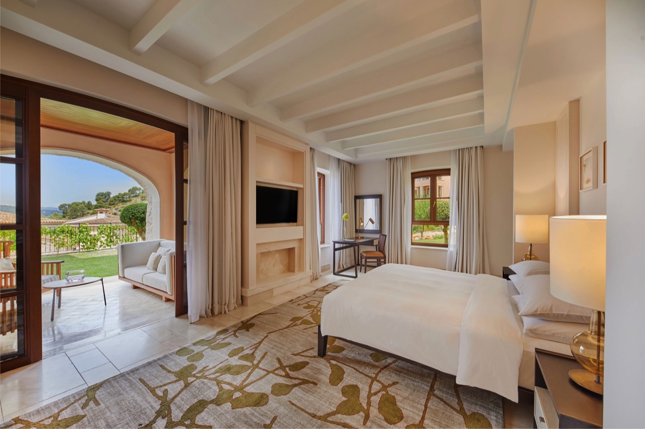 Guest room at Cap Vermell Grand Hotel with a bed, seating area, and private terrace opening onto the gardens