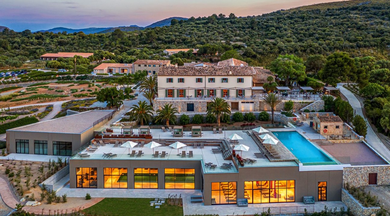Aerial view of the manor house, pool deck and spa building at dusk
