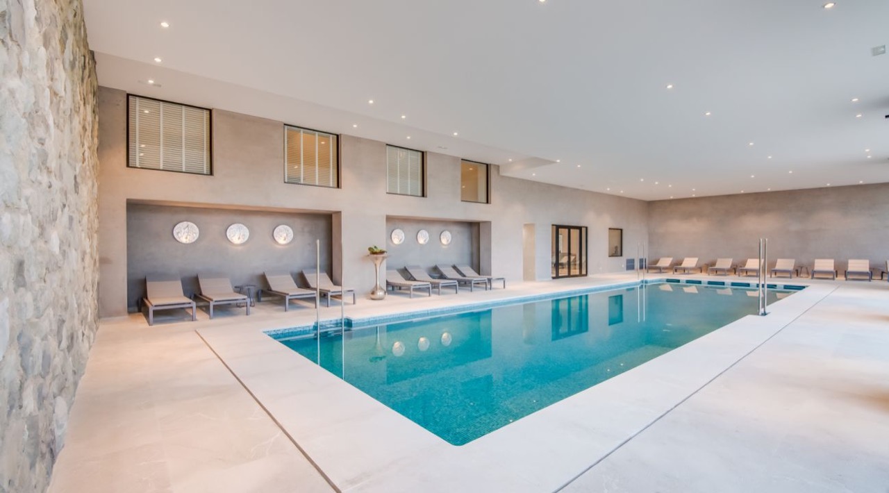 Indoor spa pool with loungers along a stone wall