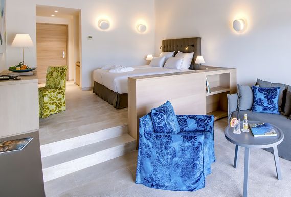 Junior suite bedroom with a blue armchair and lounge area