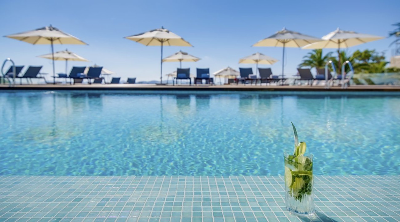 Outdoor pool with loungers and umbrellas, a drink on the pool edge