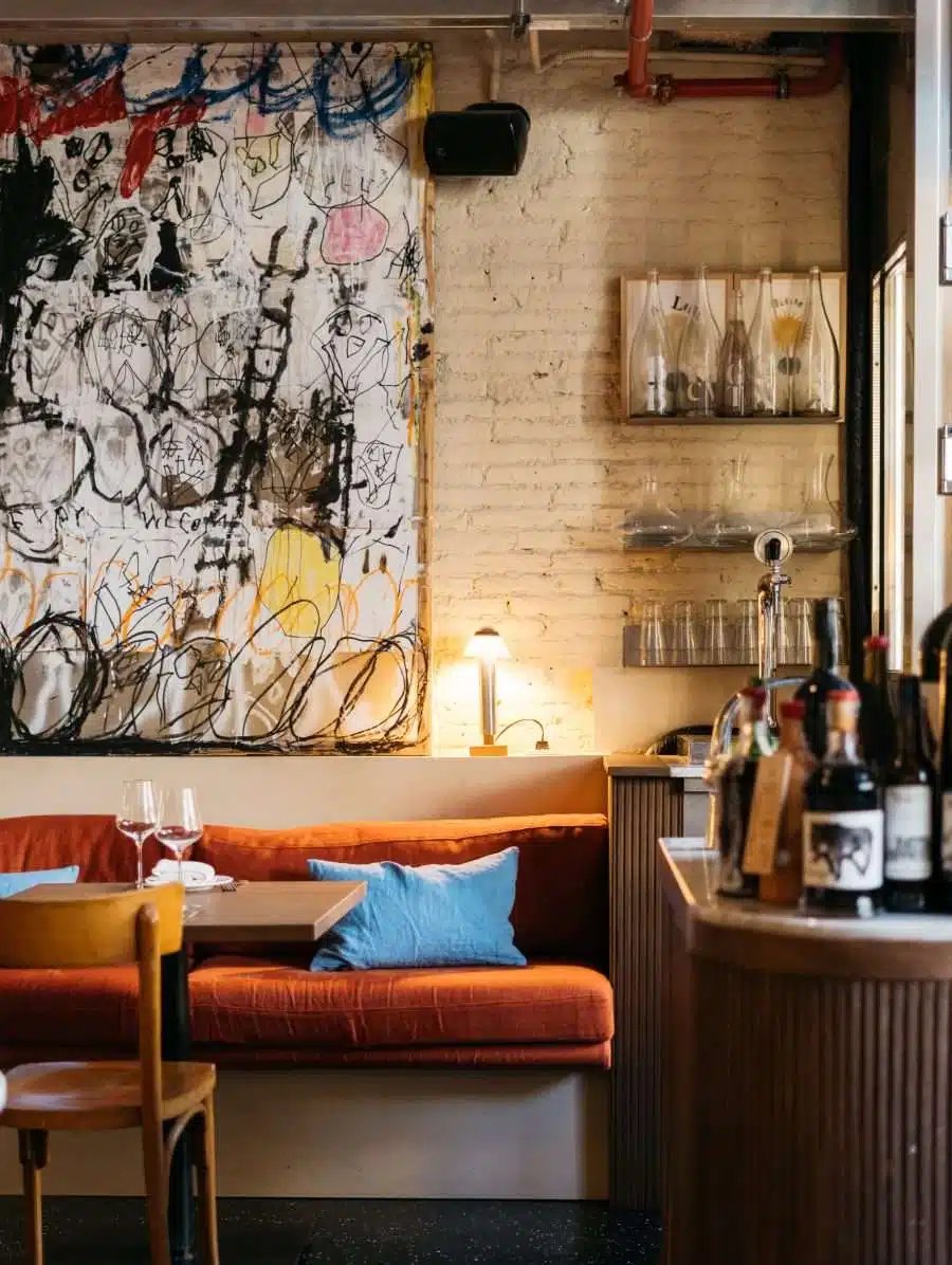 Bar and restaurant interior with an orange banquette and large abstract artwork