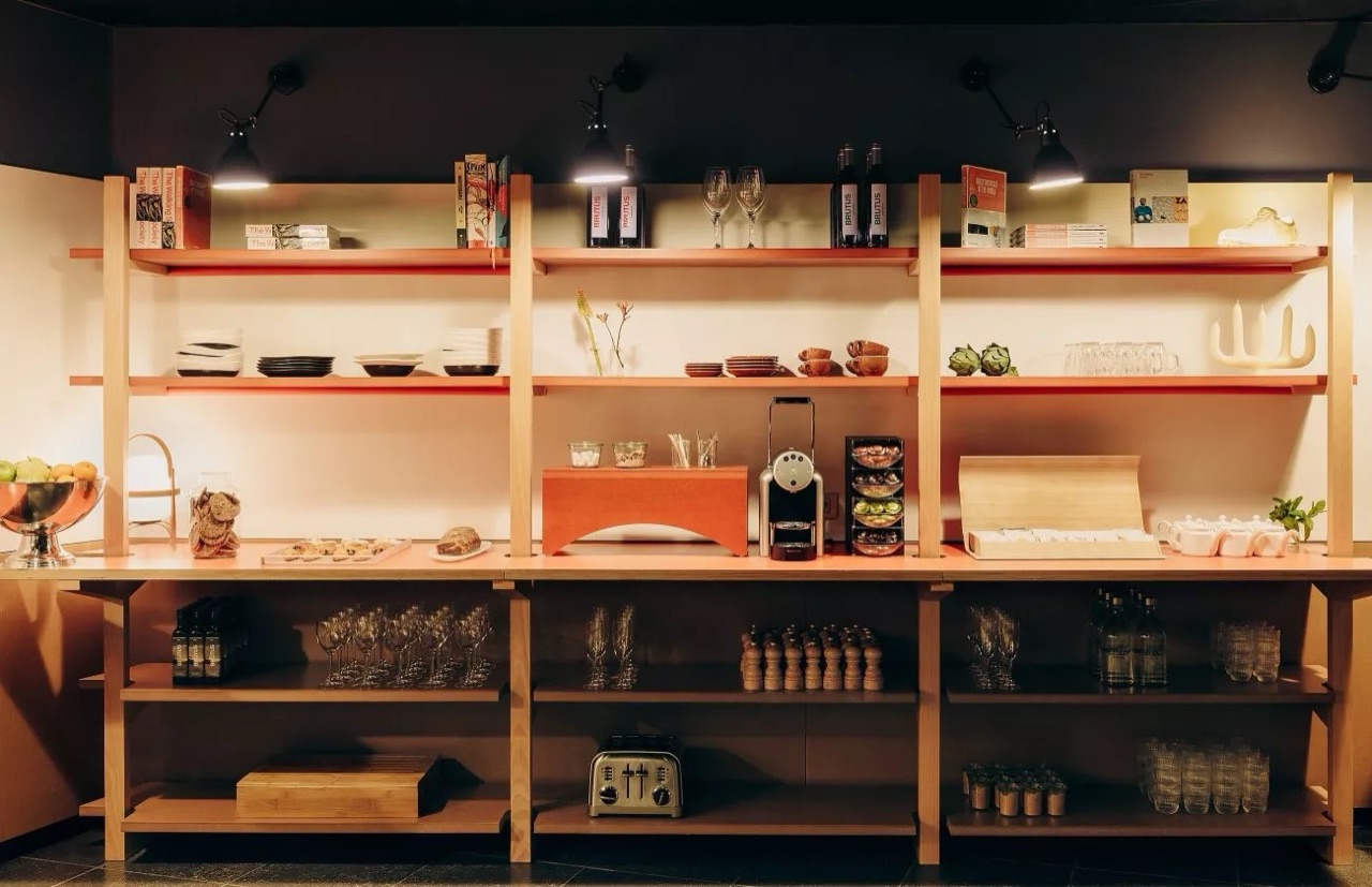 Open shelving stocked with tableware, snacks, glassware and a coffee machine at the Tentempié self-service station in Casa Camper Barcelona.