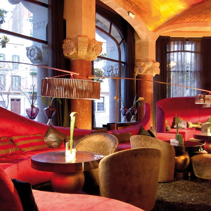 The Café Vienés lounge with red velvet seating and Modernist stone columns