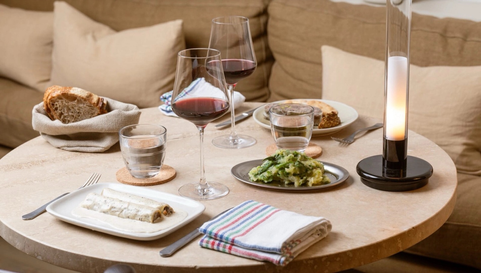 In-room dining spread with canelons, wine glasses and bread