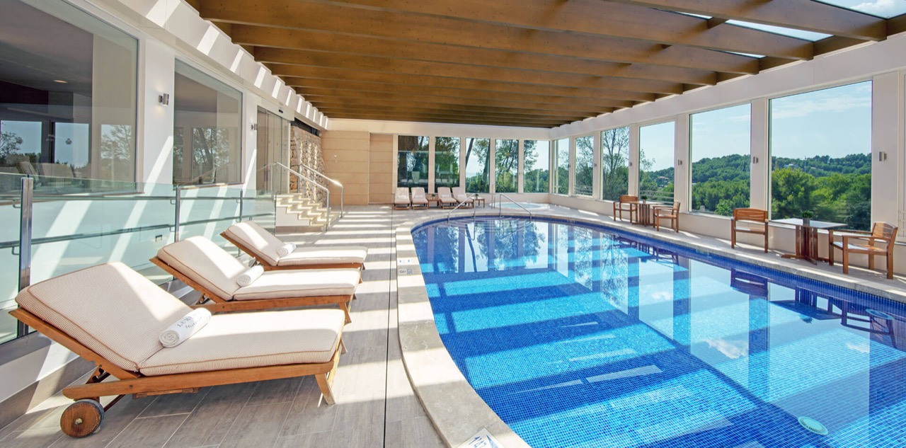 Indoor pool with loungers under a wood beamed ceiling